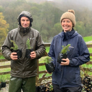 Two people holding saplings to be planted for the Celebration Wood at Wild Haweswater